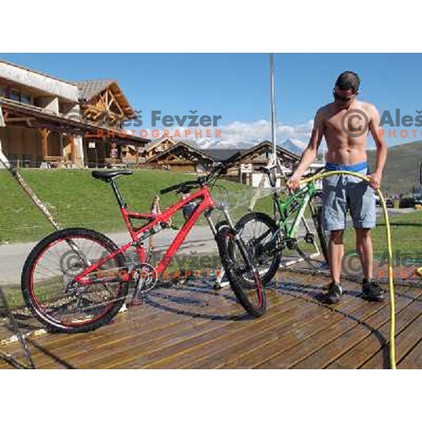 Tit Kosir washing his bike after riding MTB downhill tracks in Alpe d\'Huez ski resort at altitude between 1800 and 2700 meters above sea level on August 1, 2011 