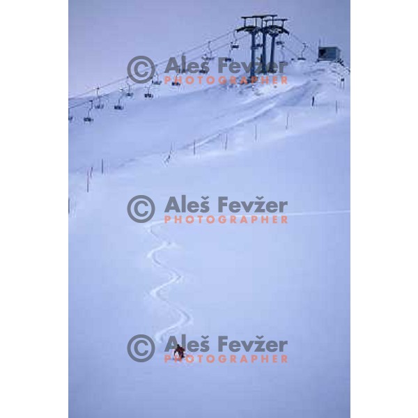 Skier in deep powder skies down from Zvoh at Krvavec ski resort, Slovenia 
