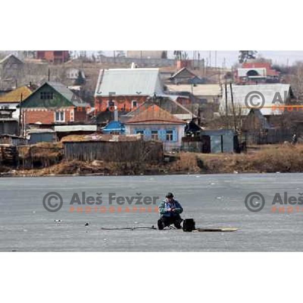 Fisherman at frozen lake near city centre of Miass in Ural, Russia 10.4.2008 