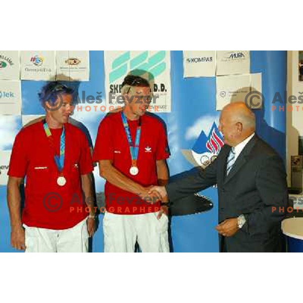 Iztok Cop and Luka Spik of Slovenia, silver medalists in rowing at Summer Olympic Games in Athens, Greece , August 2004 during reception for sponsors and press in Slovenia house receive congratulations from Janez Kocijancic 